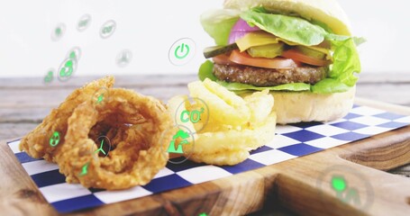 Obraz premium Displaying cheeseburger on board in studio, checkered paper, onion rings, fries, floating eco icons