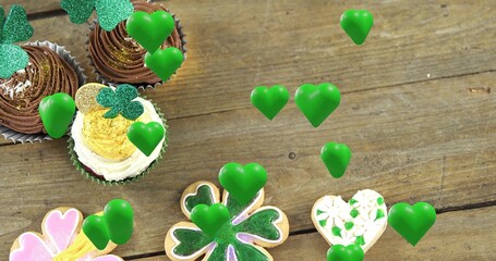 Displaying cupcakes with shamrock toppers and floating green hearts on rustic tabletop, copy space © vectorfusionart