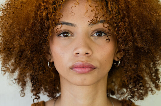African American woman posing in studio showing silver hoops, chain necklace and narrow strap top
