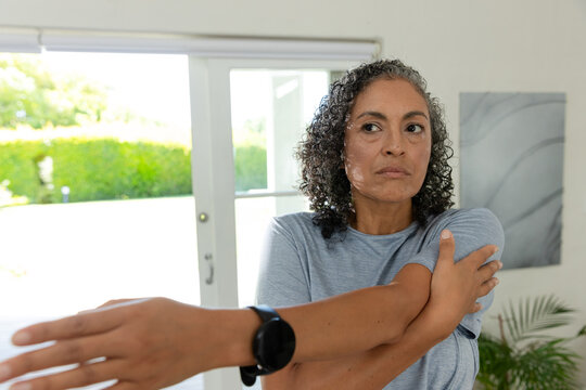African American woman stretching arm across chest near patio doors wearing smartwatch, copy space