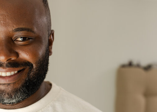 Mid adult African man in beige room smiling and looking at camera wearing crewneck, copy space