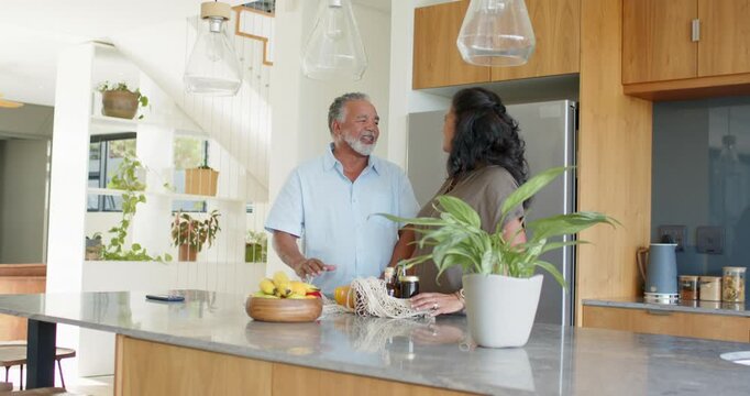 African American couple unpacking mesh bag at kitchen island, arranging fruit bowl for snack