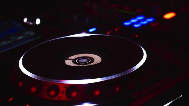 Extreme Nahaufnahme eines DJ Jog Wheels am Mischpult mit unscharfen Lichtern im Hintergrund, Nacht Club Szene