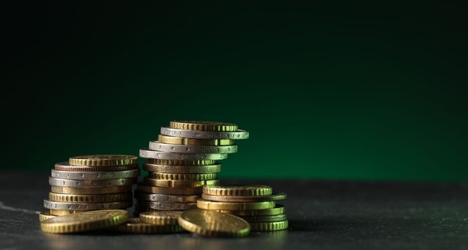 Many stacked coins on black table green background, closeup. Space for text