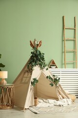 Cute wigwam with leaves and blanket in stylish child's room © New Africa