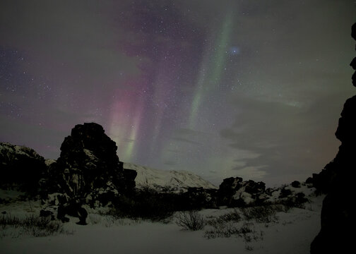 Red and green aurora borealis through the clouds in Thingvellir Iceland