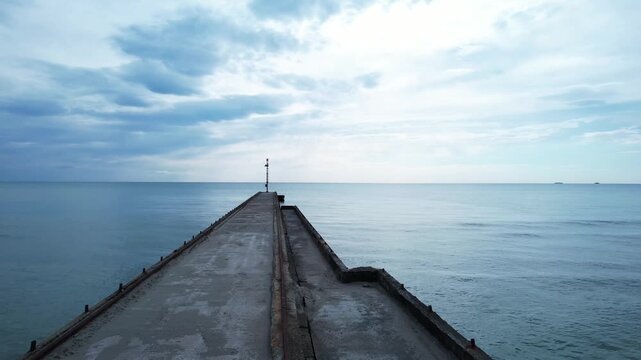 Aerial drone shot of Cinquale pier stretching into calm sea.