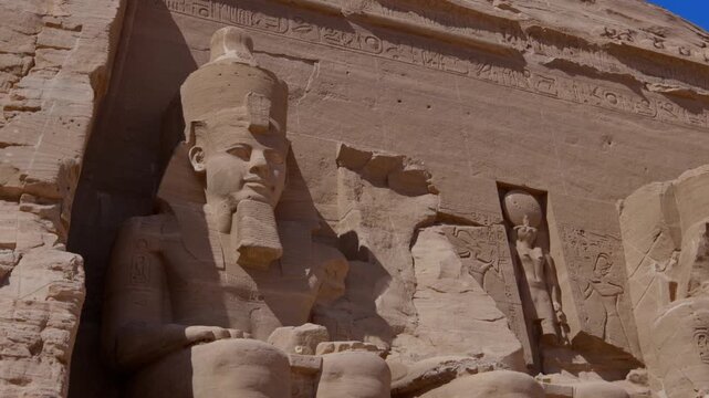 Close-up of giant Ramesses II colossi carved into rock facade at Abu Simbel temple, Egypt. Dramatic upward view of ancient sandstone pharaoh statues. Travel and history.