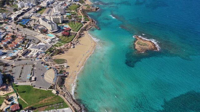 Aerial drone view of modern beachfront hotels along the coast of Protaras, Cyprus, with golden sand beaches and clear blue water attracting tourists to this Mediterranean destination