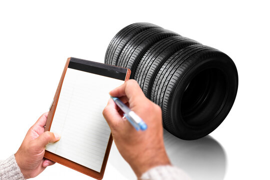Tire Inventory Inspection, A person writes on a blank notepad while checking a stack of four new black rubber tires, perfect for maintenance and shop inventory concepts.