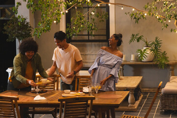 Two women and one man arranging table, preparing dinner with animated menu guiding plate layout © wavebreak3