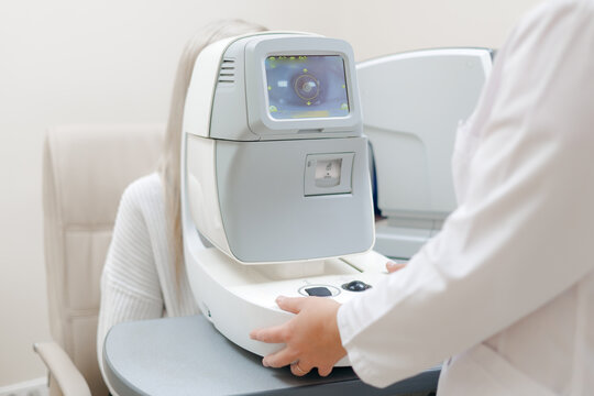 Ophthalmologist doctor adjusting autorefractor device for patient eye measurement