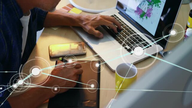 Designer holding stylus and typing, initiating network overlay from stylus to phone, mapping assets