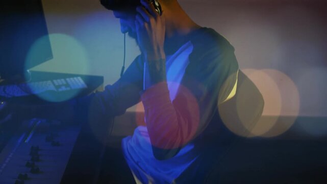 Adjusting bearded audio operator moving hands across faders in studio, raglan shirt, headphones