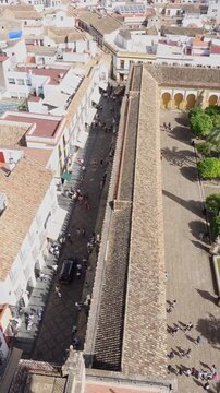 Aerial vertical view of a street next to the Mosque-Cathedral of Cordoba with people walking in a historic Andalusian city in Spain
