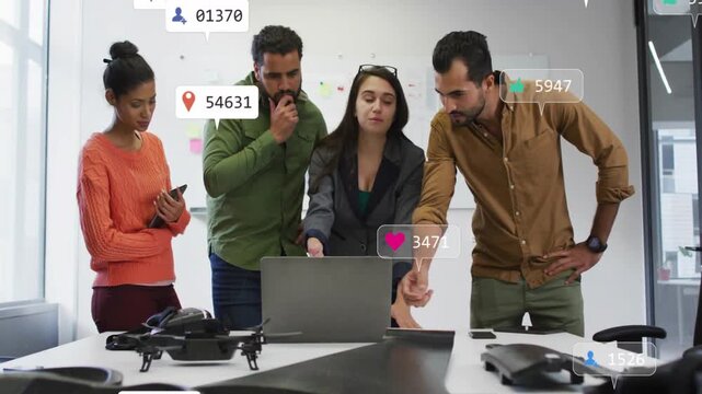 Four colleagues around laptop analyzing tech metrics as icons appearing over drones smartphone