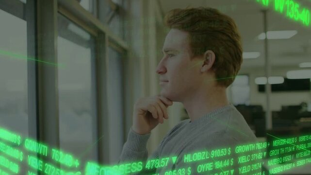 Man standing by window, holding chin, watching scrolling green ticker spurring investment decision