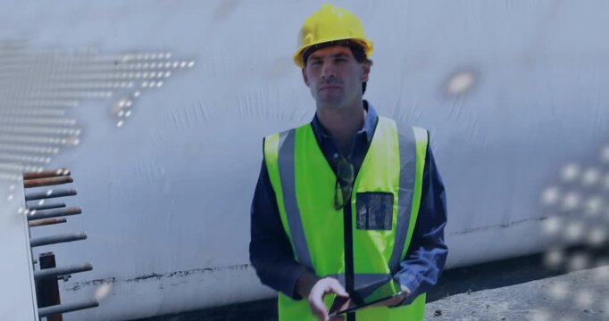 Field tech tapping tablet, inspecting tank pipes for plant safety as map and code overlay obscuring