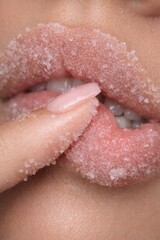 Fototapeta premium Sugar lip scrub close up with finger applying exfoliating beauty treatment 