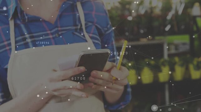 Plant shop worker tapping smartphone, tablet, updating inventory and showing animated data labels