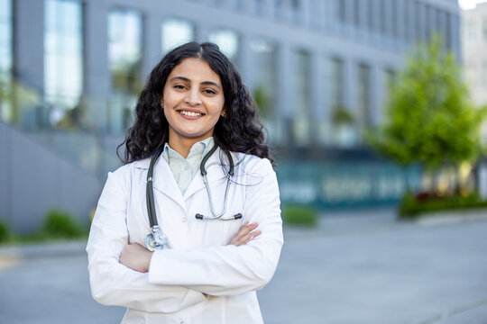 Young female doctor standing confidently at hospital entrance