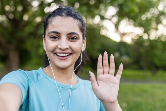 Smiling young woman waving hello during outdoor fitness exercise