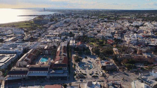 Aerial drone view of Aiya Napa, Cyprus, with coastline, cityscape, and Mediterranean Sea under warm sunlight