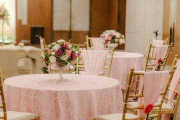 Elegant Event Setting with Floral Centerpieces and Pink Linens: A Charming Party Atmosphere for...