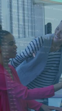 Vertical video: Seated IT dev typing after colleague pointing at screen, code overlay helping debug