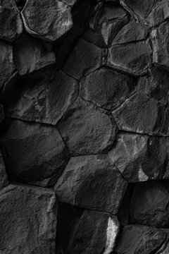 Abstract black and white texture of basalt columns with geometric pattern and rough volcanic rock surface