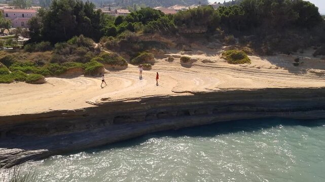 Scenic view of tourists walking on the unique sandstone rock formations of Canal d'Amour in Sidari Corfu Greece overlooking the turquoise Ionian Sea on a sunny summer day