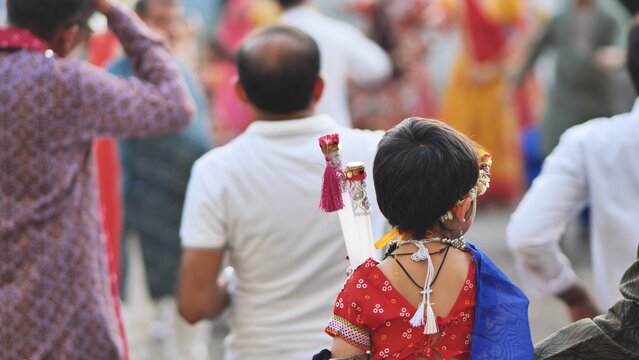 Child in traditional attire holding garba sticks celebrating Ganesh Chaturthi festival