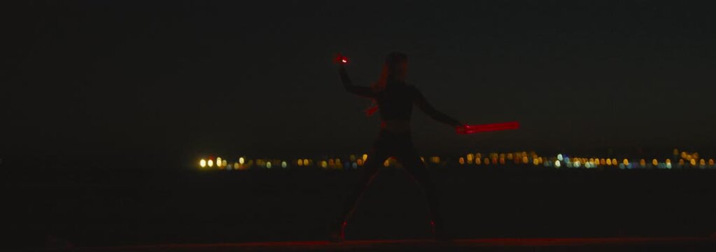 Woman warrior fighting with red light swords at night