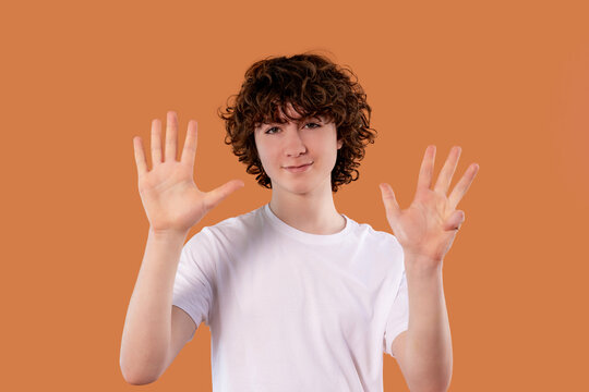 A young person stands in front of an orange background