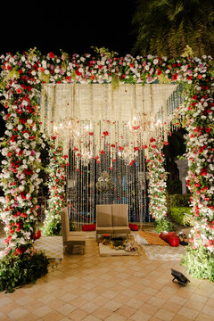 Elegant outdoor event setup at night with lush floral arch, sparkling crystal and bead decor, and cozy seating arrangements, perfect for upscale celebrations