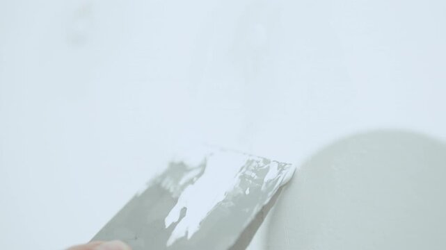 Handyman filling holes on white wall with putty knife, wall preparation process, high quality 10 bit 4K.