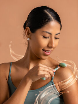 Woman massaging shoulder with jade roller and skincare serum effect