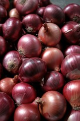 Obraz premium A tightly packed, close-up pile of raw red and some yellowish onions on a concrete surface, overhead view