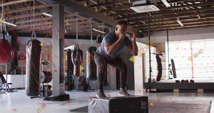 Man doing box jumps in gym, crouching initiating jump, landing stabilizing, stepping down for power