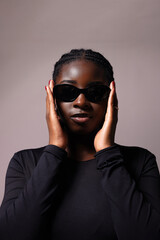 Fototapeta premium African American young woman wears sunglasses looking at the camera and posing over white background. 