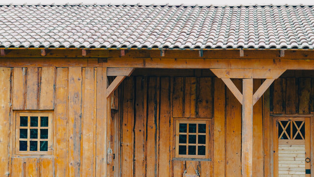 Rustic wooden cabin exterior with tiled roof and small windows