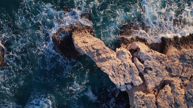 Aerial drone view of the Bridge of Love, a natural rock arch formation in Ayia Napa, Cyprus. Turquoise waves flow beneath the limestone arch