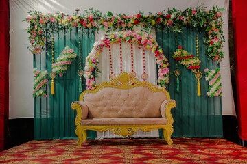 Elegant golden sofa with plush upholstery on a red ornate carpet, set against a teal backdrop...
