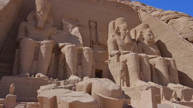 Close-up of giant Ramesses II colossi carved into rock facade at Abu Simbel temple, Egypt. Dramatic upward view of ancient sandstone pharaoh statues. Travel and history.