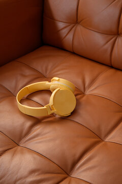Yellow headphones resting on brown leather sofa