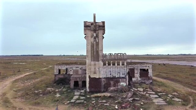 Drone shot moving away from the ruined slaughterhouse structure. Gloomy atmosphere and threatening sky over the disaster zone in Villa Epecuen.