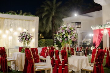 Elegant outdoor evening event reception with beautifully decorated tables and chairs, soft...