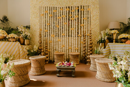 Elegant Traditional Indian Wedding Decor with Fresh White and Yellow Flowers, Golden Accents, and Woven Stools for a Festive Celebration