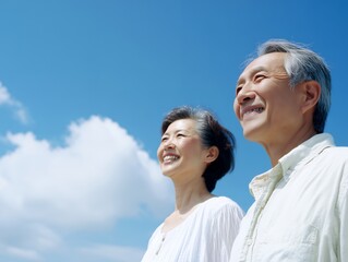 Obraz premium 青空の下で希望に満ちた表情で遠くを見つめる笑顔のシニア夫婦の上半身