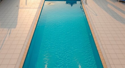 Fototapeta premium Pristine swimming pool with clear blue water surrounded by tiled deck